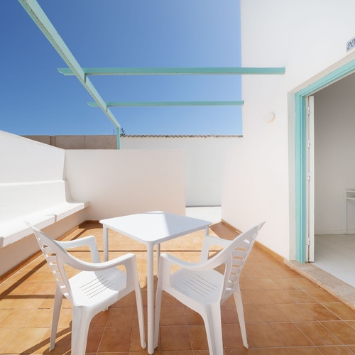 ein Tisch und Stühle stehen auf einem Balkon mit einem Schild an der Tür , das sagt ' zimmer '