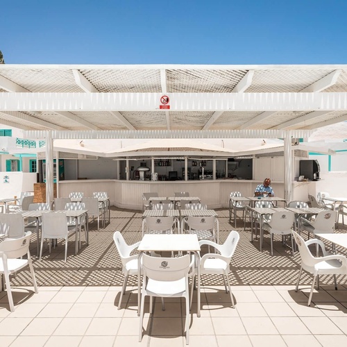 ein Mann sitzt vor einer Bar mit weißen Tischen und Stühlen