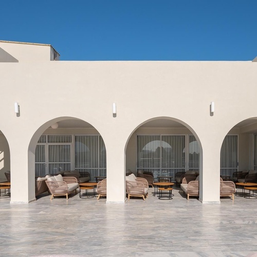 a white building with arches and chairs in front of it