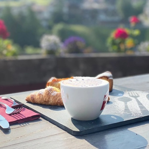 a tray with a cup of coffee and a croissant on it