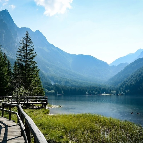 a wooden walkway leading to a lake with mountains in the background