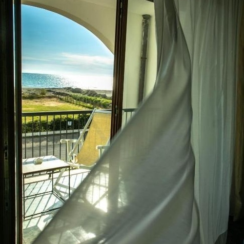 eine weiße Vorhänge hängt an einem Fenster mit Blick auf den Ozean