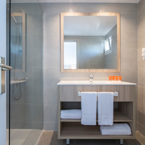 um banheiro com uma pia de madeira e um espelho