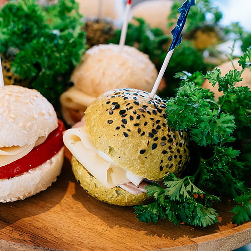 Mini-burgers avec garnitures au fromage, jambon et poivrons rouges, servis sur un plateau en bois avec du persil, parfaits pour Smy: Corporativa.