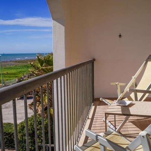 Liegestühle und Tisch auf einem Balkon mit Blick auf den Ozean