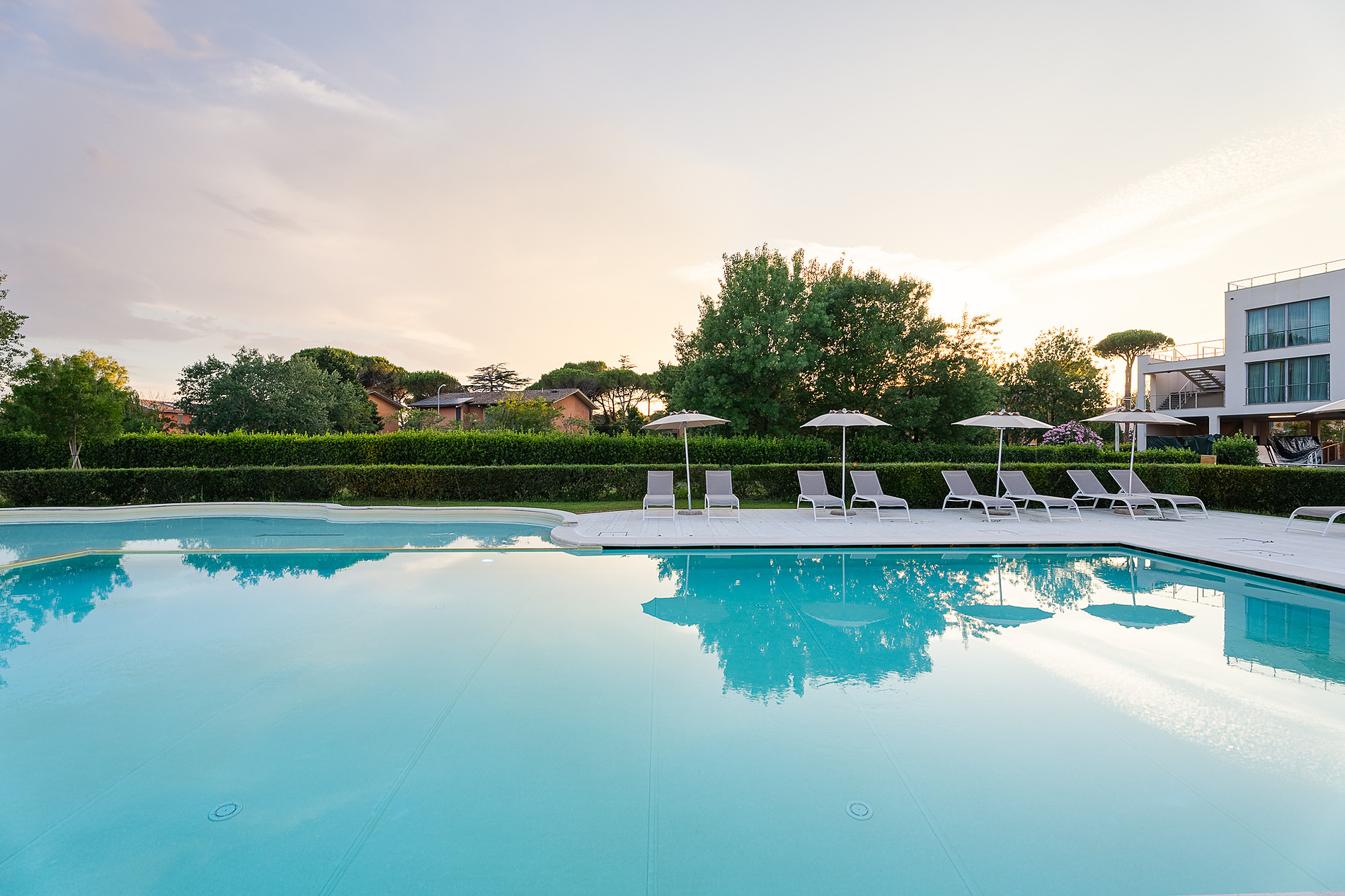 Hotel Pisa Plaza 5* | Web Oficial: Fachada moderna con jardín florido y barco histórico.