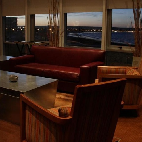 a living room with a couch and chairs with a view of the ocean