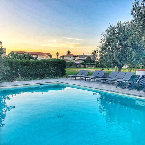 Liegestühle stehen um einen großen Swimmingpool
