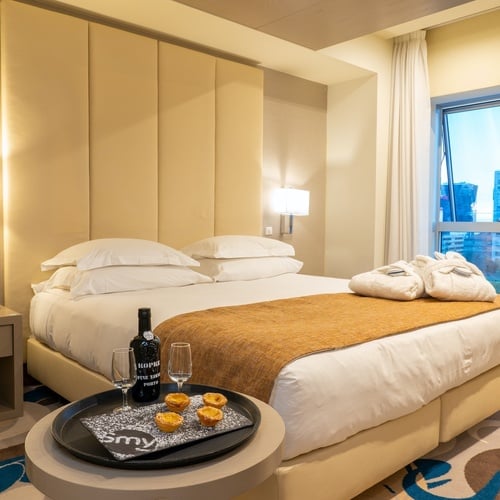 a hotel room with a bed and a bottle of porto on a table