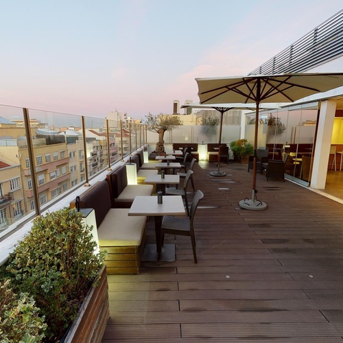a balcony with tables and chairs and a large umbrella