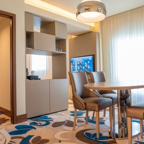 a hotel room with a table and chairs and a flat screen tv
