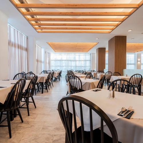 a restaurant with white tables and black chairs