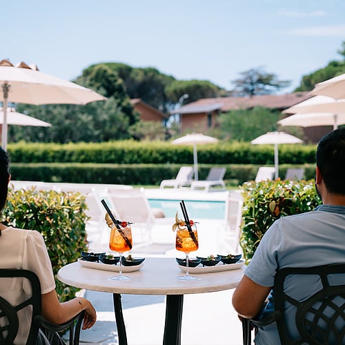 Couple with cocktails enjoying the poolside view at Smy: Corporativa.