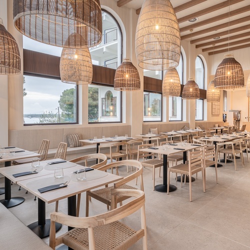Sala de jantar corporativa Smy com luz natural e lustres de vime.