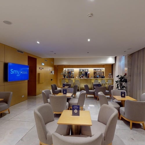 a room with tables and chairs and a tv that says sky hotel