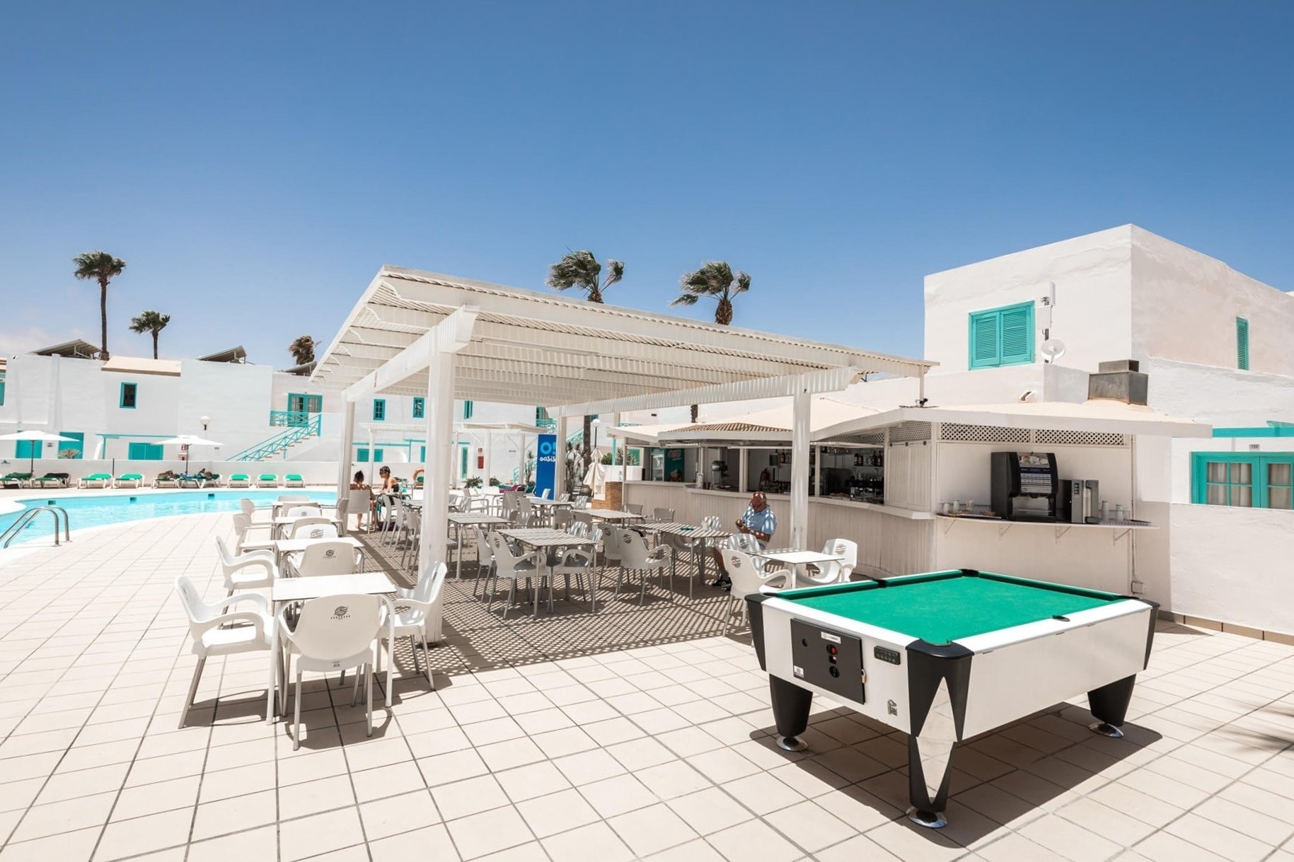 ein Mann sitzt vor einer Bar mit weißen Tischen und Stühlen