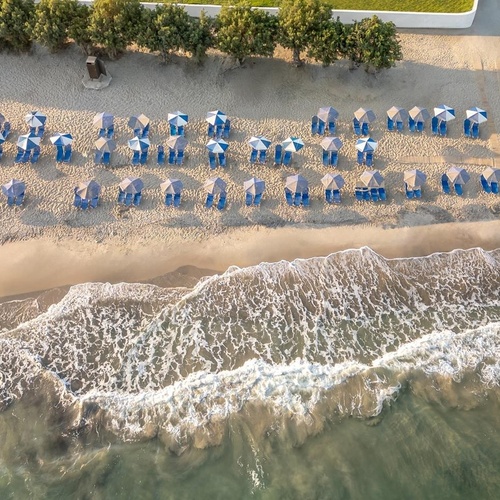 an aerial view of a beach with umbrellas and chairs