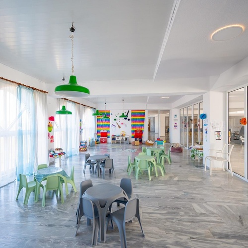 a room with tables and chairs and a sign that says ' kindergarten ' on it