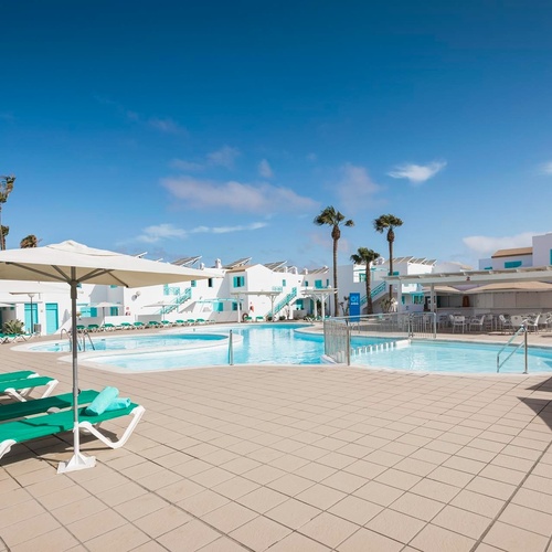 ein großer Swimmingpool mit Liegestühlen und Sonnenschirmen