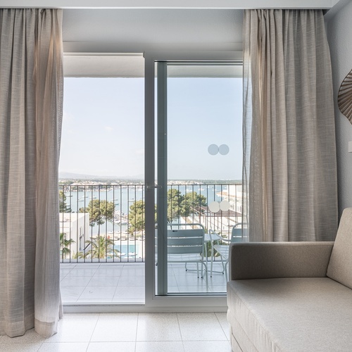 Sofá moderno em quarto de hotel com vista mar e varanda. Ideal para Smy: Corporativa.
