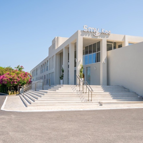 a large white building with stairs leading up to the entrance of smy kos