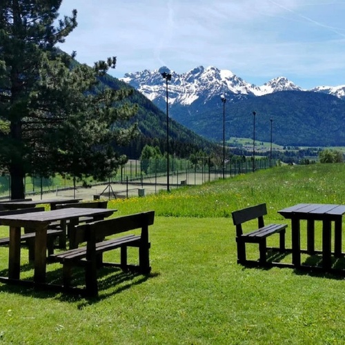 a picnic area with tables and benches with mountains in the background