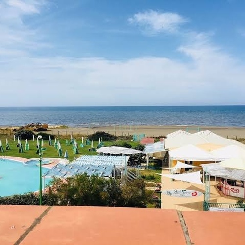 Es gibt einen Pool und viele Sonnenschirme am Strand .