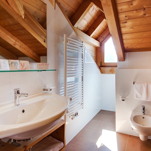 a bathroom with a sink and a bidet under a wooden ceiling