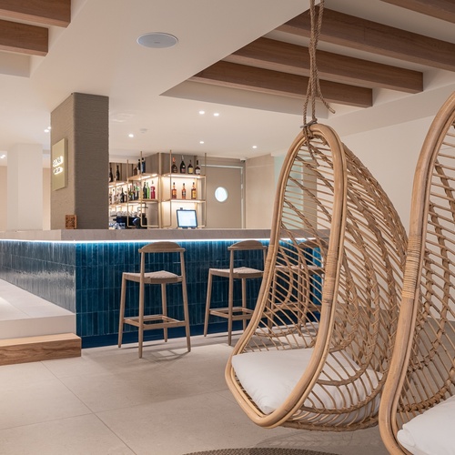 Área lounge Smy: Corporativa com cadeiras suspensas de vime e bar.