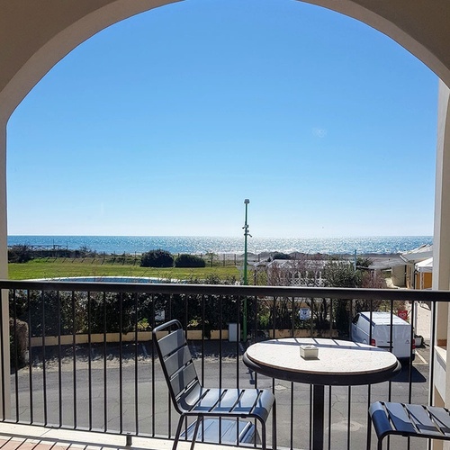 ein Tisch und ein Stuhl auf einem Balkon mit Blick auf das Meer