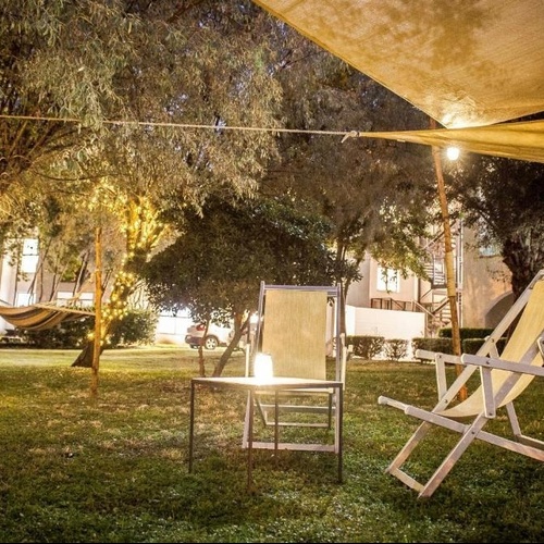 ein Liegestuhl sitzt unter einem Sonnenschirm im Gras