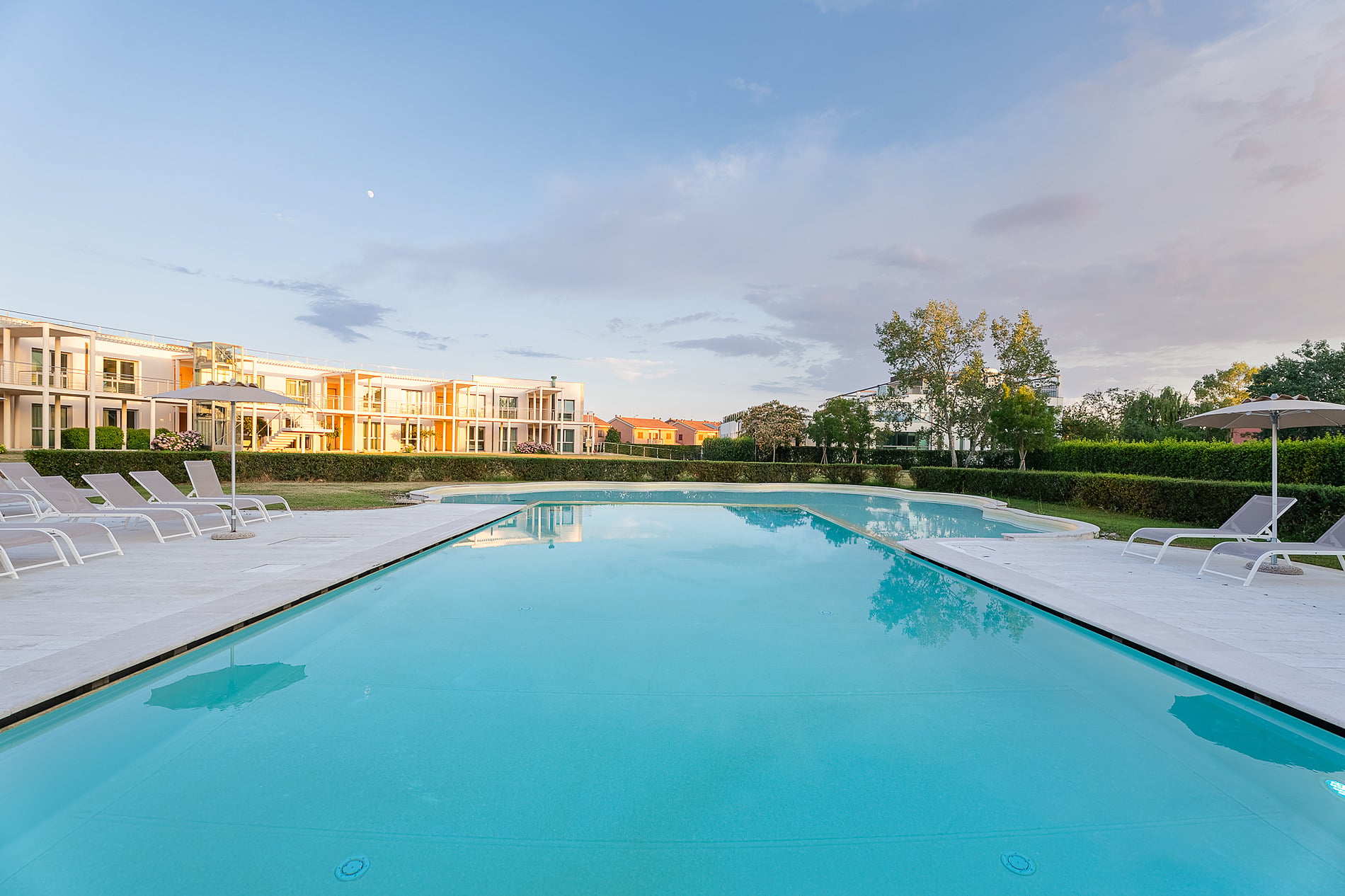 Hotel Pisa Plaza 5* | Official Website: Modern facade with a flowered garden and historical boat.