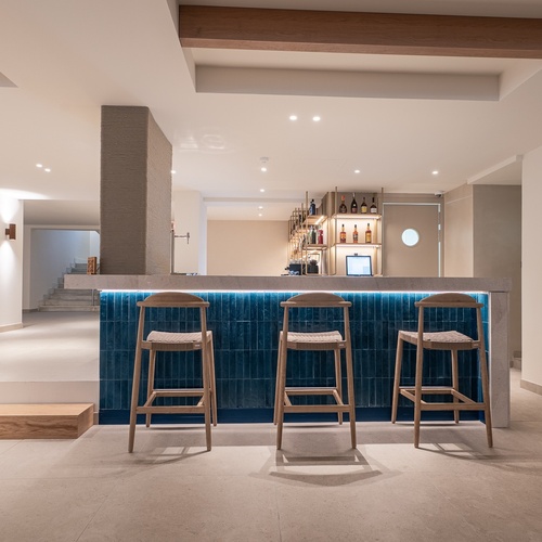 Bar corporativo moderno com banquetas de madeira e iluminação azul.