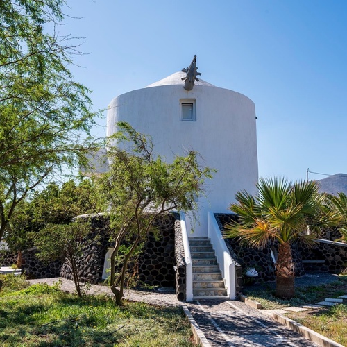 un moulin à vent blanc est entouré d' arbres et de palmiers