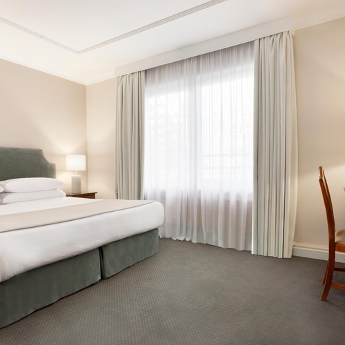 a hotel room with a bed a desk and a television