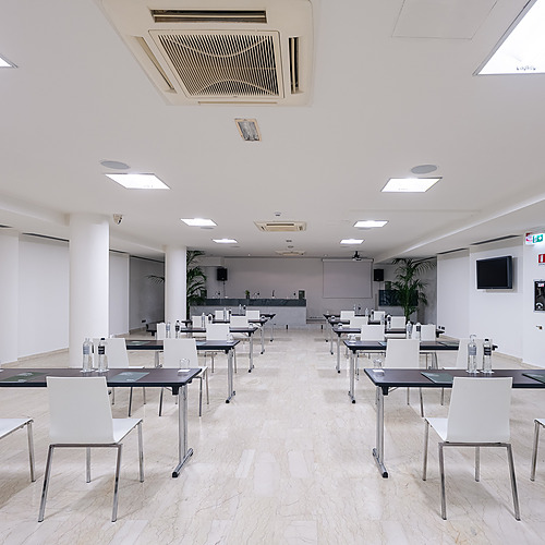 Salle de conférence moderne à l'hôtel, aménagée pour Smy: Corporativa, avec tables et chaises blanches.