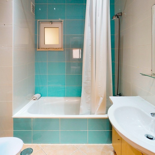 a bathroom with blue tiles and a white shower curtain