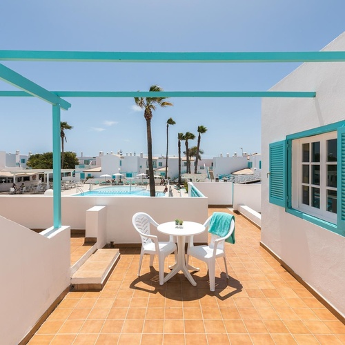 ein weißes Gebäude mit blauen Fensterläden und einem Tisch und Stühlen