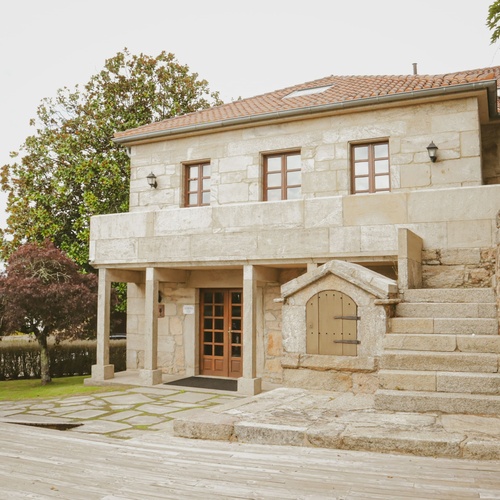 una casa de piedra con un balcón y una puerta de madera
