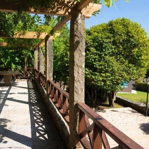 una pasarela de madera conduce a una piscina rodeada de árboles