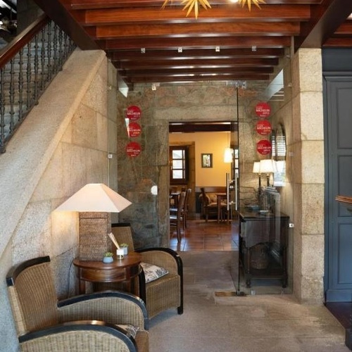 una puerta de vidrio que conduce a una habitación con sillas y una lámpara