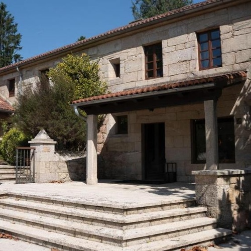 una gran casa de piedra con un techo de tejas rojas
