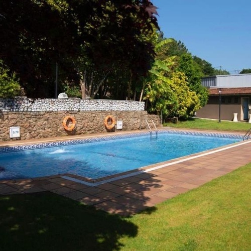 Piscina exterior del SNO: Pazo de Adran con tumbonas y zona ajardinada.