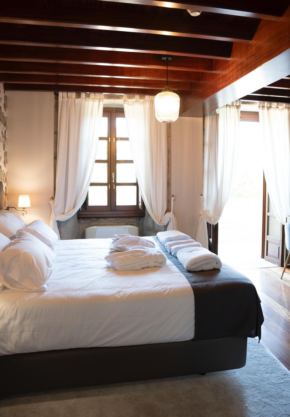 una habitación con una cama y una ventana con cortinas blancas