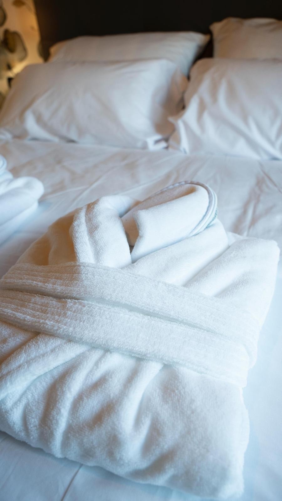 una bata blanca está sobre una cama con sábanas blancas