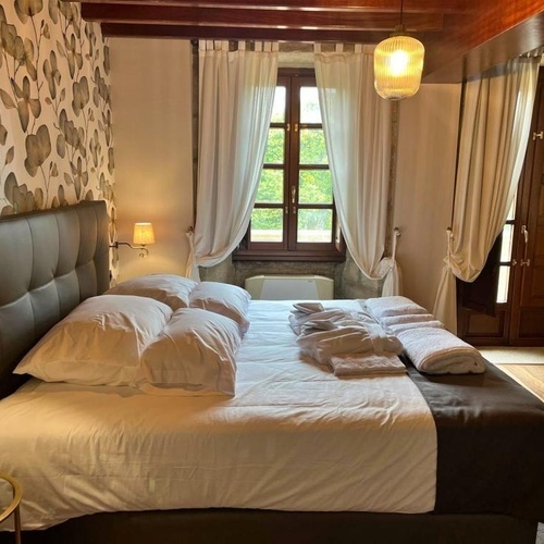 una habitación con una cama y una ventana con cortinas blancas