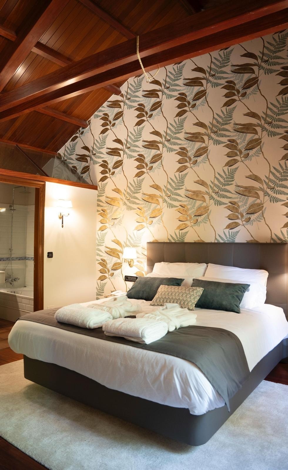 una habitación con una cama y una pared con un patrón de hojas