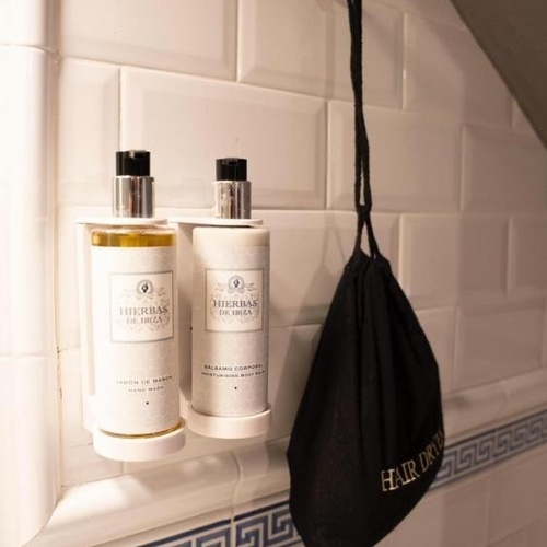dos botellas de hierbas de ibiza están en un estante en un baño