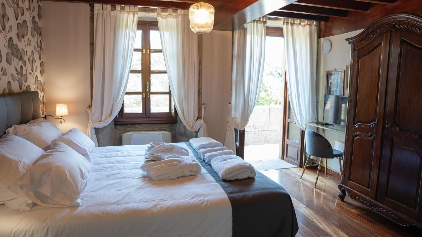 una habitación con una cama y una ventana con cortinas blancas