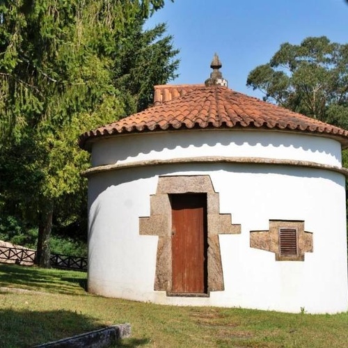 un pequeño edificio blanco con un techo de tejas rojas y una puerta de madera
